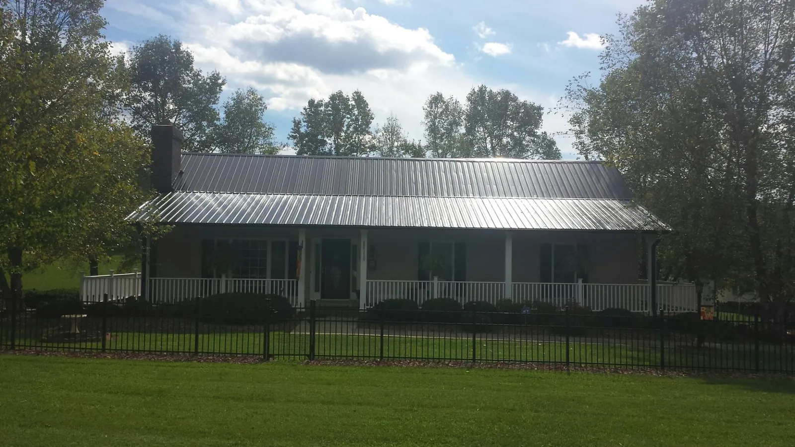 Gray metal roof on a brick ranch with a full width front porch — Gutter Guard Installation work by our crew in Orient