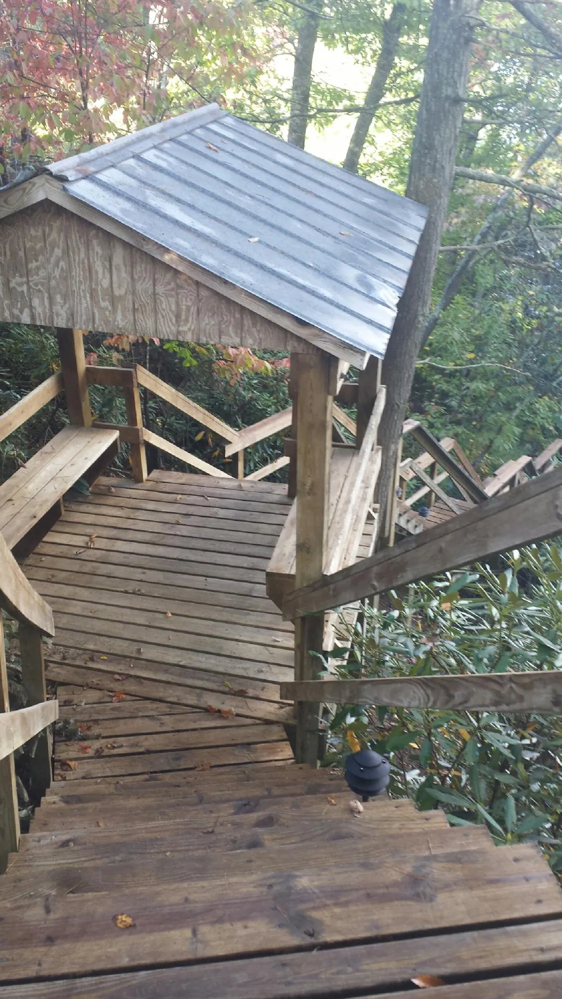 Metal roofed shelter over wooden steps on a wooded walkway — Skylight Repair & Installation work by our crew in Orient