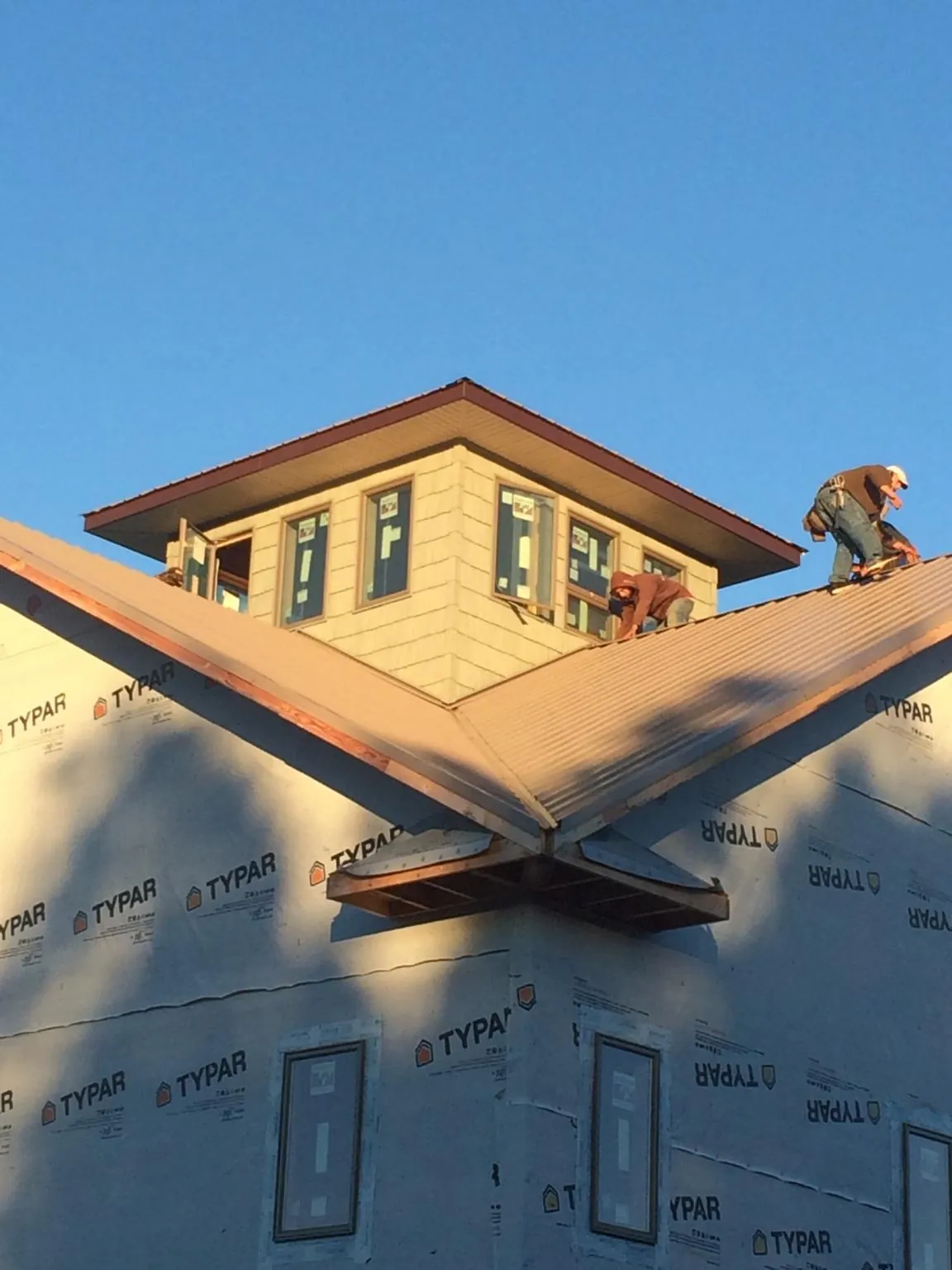 Roofers working around a rooftop cupola on a new metal roof at sunset — Roof Waterproofing in Orient by Roofing Brothers